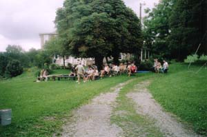 People sitting and singing opening song under the Horse Chestnut tree.