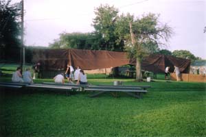 A shot of the brown canvas canopy being set up by men.